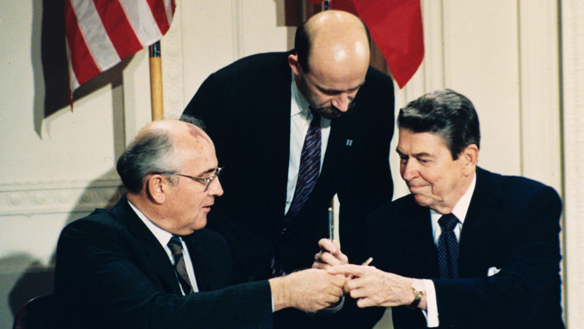 FILE - In this Dec. 8, 1987 file photo U.S. President Ronald Reagan, right, and Soviet leader Mikhail Gorbachev exchange pens during the Intermediate Range Nuclear Forces Treaty signing ceremony in the White House East Room in Washington, D.C. Gorbachev's translator Pavel Palazhchenko stands in the middle. Trump's announcement that the United States would leave the Intermediate-Range Nuclear Forces, or INF, treaty brought sharp criticism on Sunday Oct. 21, 2018, from Russian officials and from former Soviet President Mikhail Gorbachev, who signed the treaty in 1987 with President Ronald Reagan. (AP Photo/Bob Daugherty, File)