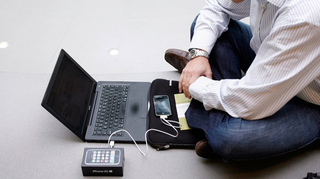 Man Setting Up iPhone on His Laptop