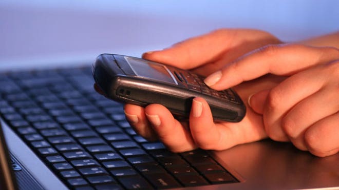 Man Using Cell Phone and Laptop