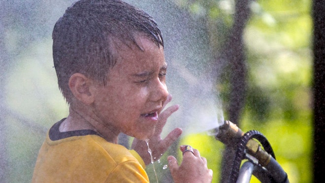 July 6, 2012: Six-year-old Alexander Merrill of Sioux Falls, S.D., cools off in a cloud of mist at the Henry Doorly Zoo in Omaha, Neb., as temperatures reached triple digits. (AP Photo/Nati Harnik)