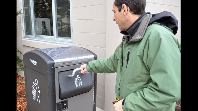 Dec. 5, 2012: Rich Valcourt checks on a BigBelly solar-powered waste disposal unit at Natick Soldier Systems Center, Mass. NSSC has 12 of the units positioned across the installation. (Bob Reinert, USAG Natick)
