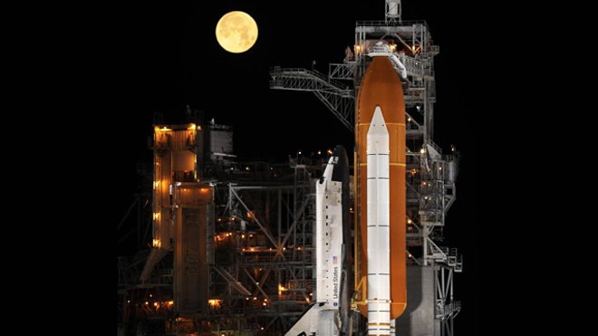 Behind the shuttle, a nearly full moon sets