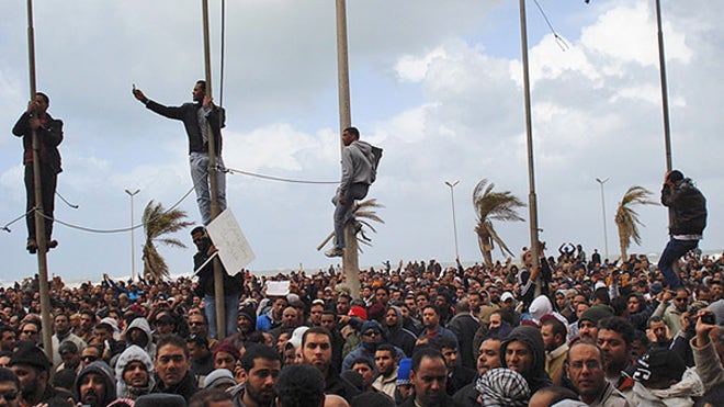 Libyan protesters climb poles