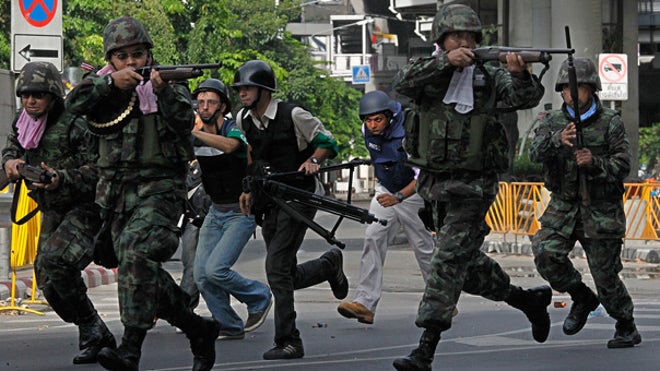 Thai soldiers run with guns