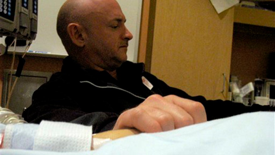 Gifford and Mark Kelly hold hands at bedside