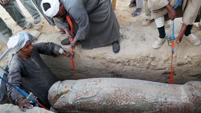 Egyptian men digging up a preserved wooden sarcophagus