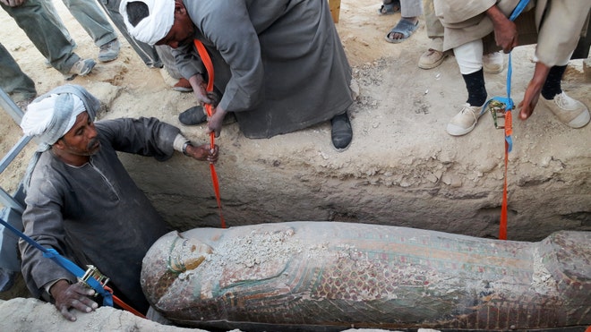 Egyptian men digging up a preserved wooden sarcophagus