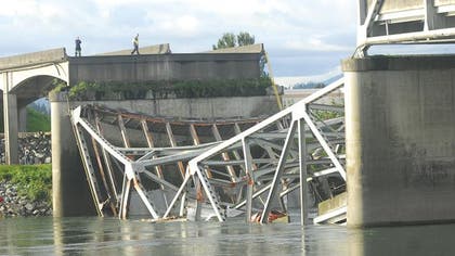 A truck carrying an oversize load struck a bridge on the major thoroughfare between Seattle and Canada, sending a section of the span and two vehicles into the Skagit River below, though all three occupants suffered only minor injuries.