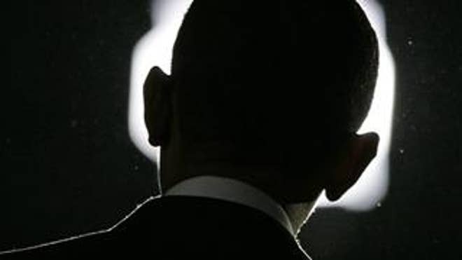 Barack Obama is silhouetted by a light.
