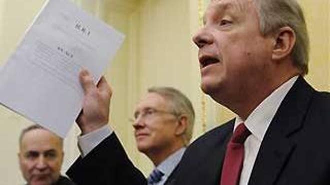 Sen. Richard Durbin, D-Ill., right, alongside Sen. Charles Schumer, D-N.Y., left, and Senate Majority Leader Harry Reid, holds a copy of the House stimulus bill as he talks to reporters on Capitol Hill Thursday. (AP Photo)