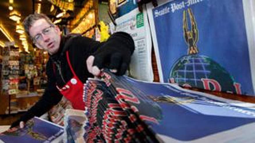 March 17: A newspaper vendor grabs multiple copies of the final edition of the Seattle Post-Intelligencer in downtown Seattle. The edition ended a heritage stretching back nearly 146 years, when the Seattle Gazette, the P-I's predecessor, began publishing in December 1863. (AP photo)