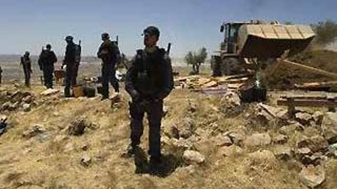 Israeli police officers stand guard as a bulldozer demolishes a makeshift structure in an unauthorized outpost near the West Bank city of Ramallah Wednesday. (Reuters Photo)