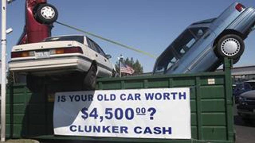 Used cars are seen in a dumpster to draw attention to the "Cash for Clunkers" program