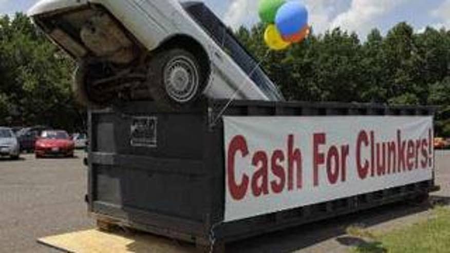 An old car dropped in an industrial trash bin serves as an ad for the cash for clunkers program at Battlefield Ford in Culpeper, Va., Aug. 1. (Reuters Photo)