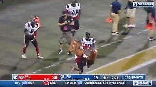 College football players break trophy after victory against rival school