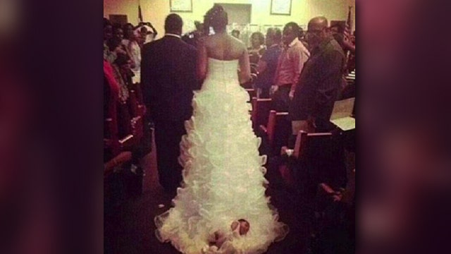 Bride walks down aisle with newborn tied to bottom of dress