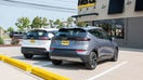 A Summit White 2023 Chevrolet Bolt EV and a Gray Ghost Metallic 2023 Chevrolet Bolt EUV parked in front of a Hertz rental location in Michigan. 