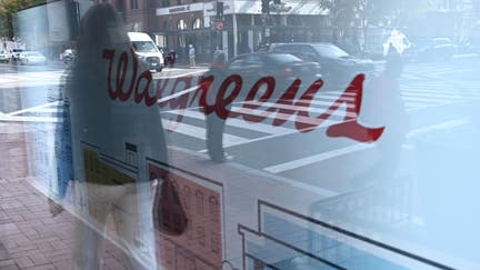 A pedestrian is reflected in a window of Walgreens in Washington, DC, on November 2, 2022. - CVS Health said they had agreed to pay approximately $5 billion over 10 years to "resolve all opioid lawsuits and claims" against them by states and cities. Walgreens and Walmart have also agreed to settlements of at least $4 billion and $3 billion, according to a report by Bloomberg. (Photo by Brendan SMIALOWSKI / AFP) (Photo by BRENDAN SMIALOWSKI/AFP via Getty Images)