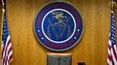 The Federal Communications Commission (FCC) seal hangs inside a meeting room at the headquarters ahead of a open commission meeting in Washington, D.C., U.S., on Thursday, Dec. 14, 2017. The FCC is slated to vote to roll back a 2015 utility-style classification of broadband and a raft of related net neutrality rules, including bans on broadband providers blocking and slowing lawful internet traffic on its way to consumers. 