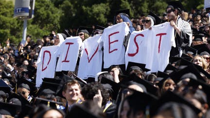 Student graduates hold white t-shirts stating the message, "divest," as they protest during the UC Berkeley graduation held at California Memorial Stadium following weeks of pro-Palestinian protests in Berkeley, Calif. on Saturday, May 11, 2024.