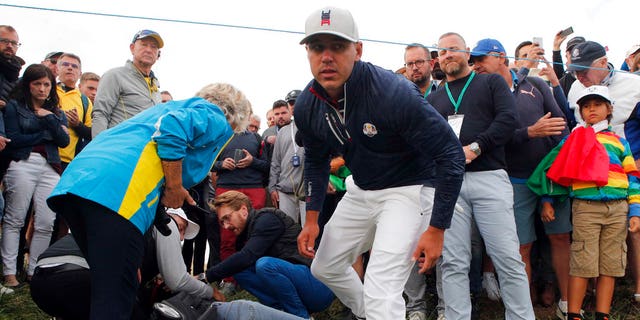 Brooks Koepka looks at the camera after checking the name of a fan that he hit with a stray tee-shirt at the Ryder Cup