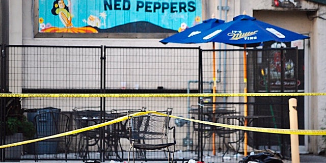 Police tape drapes over a chair near a pile of shoes after a mass shooting in Dayton, Ohio on Sunday, Aug, 4, 2019. (Marshall Gorby/Dayton Daily News via AP)