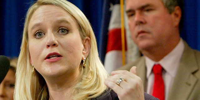 Tiffany Carr, then the executive director of Florida Coalition Against Domestic Violence, left, speaks at a news conference held by Gov. Jeb Bush, background right, Sept. 28, 2004, in Tallahassee, Fla. (Associated Press)