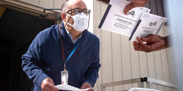 An employee of the Philadelphia Commissioners Office examines ballots at a satellite election office at Overbrook High School in Philadelphia. (AP Photo/Laurence Kesterson)