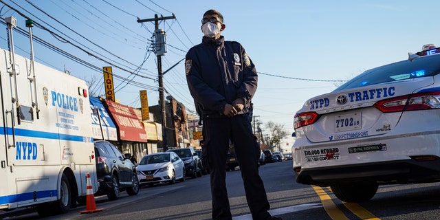 Police maintain a perimeter outside a crime scene, Tuesday, Nov. 24, 2020, in the Queens borough of New York. (AP Photo/John Minchillo)