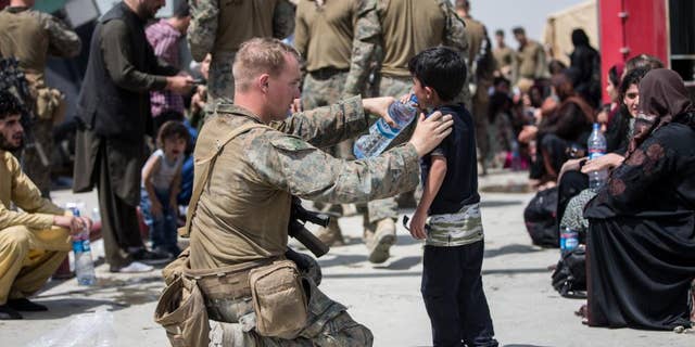 A Marine with the 24th Marine Expeditionary Unit (MEU) provides fresh water to a child during an evacuation at Hamid Karzai International Airport, Kabul, Afghanistan, Aug. 20. U.S. service members are assisting the Department of State with an orderly drawdown of designated personnel in Afghanistan. (U.S. Marine Corps photo by Sgt. Samuel Ruiz).