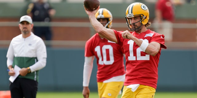Green Bay Packers' quarterback Aaron Rodgers (12) passes while head coach Matt LaFleur and quarterback Jordan Love (10) watch during NFL football training camp Wednesday, July 28, 2021, in Green Bay, Wis.