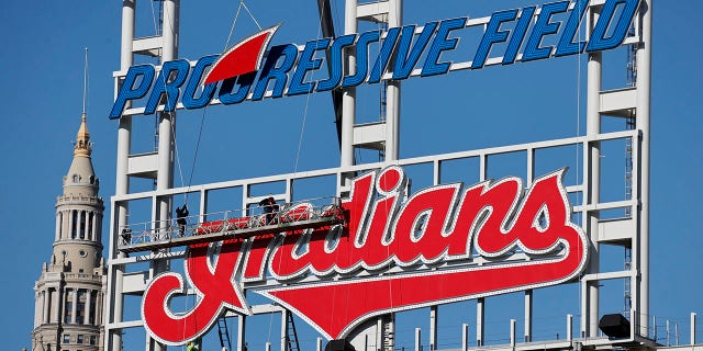Workers begin to remove the Cleveland Indians sign from above the scoreboard at Progressive Field, Tuesday, Nov. 2, 2021, in Cleveland. Known as the Indians since 1915, Cleveland's Major League Baseball team will be called Guardians. (AP Photo/Ron Schwane)