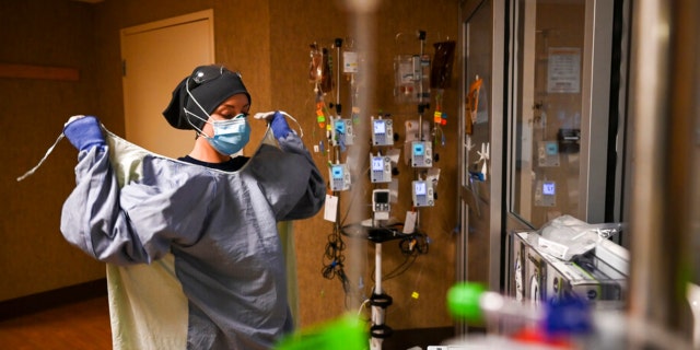 North Memorial Health Hospital Critical Care Nurse Kayla Lynch donned a protective gown before entering the room of a COVID-19 patient during her shift Monday afternoon. (AARON LAVINSKY/ Star Tribune/ Associated Press)