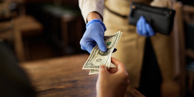 Biden's IRS plans to crack down on server tips 2 A waitress collects a tip from a customer.