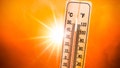 Background for a hot summer or heat wave, orange sky with with bright sun and thermometer