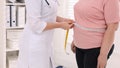 Nutritionist measuring overweight woman&apos;s waist with tape in clinic, closeup - Fox News