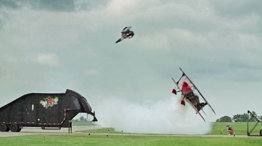 Motorcycle jumps over flying plane