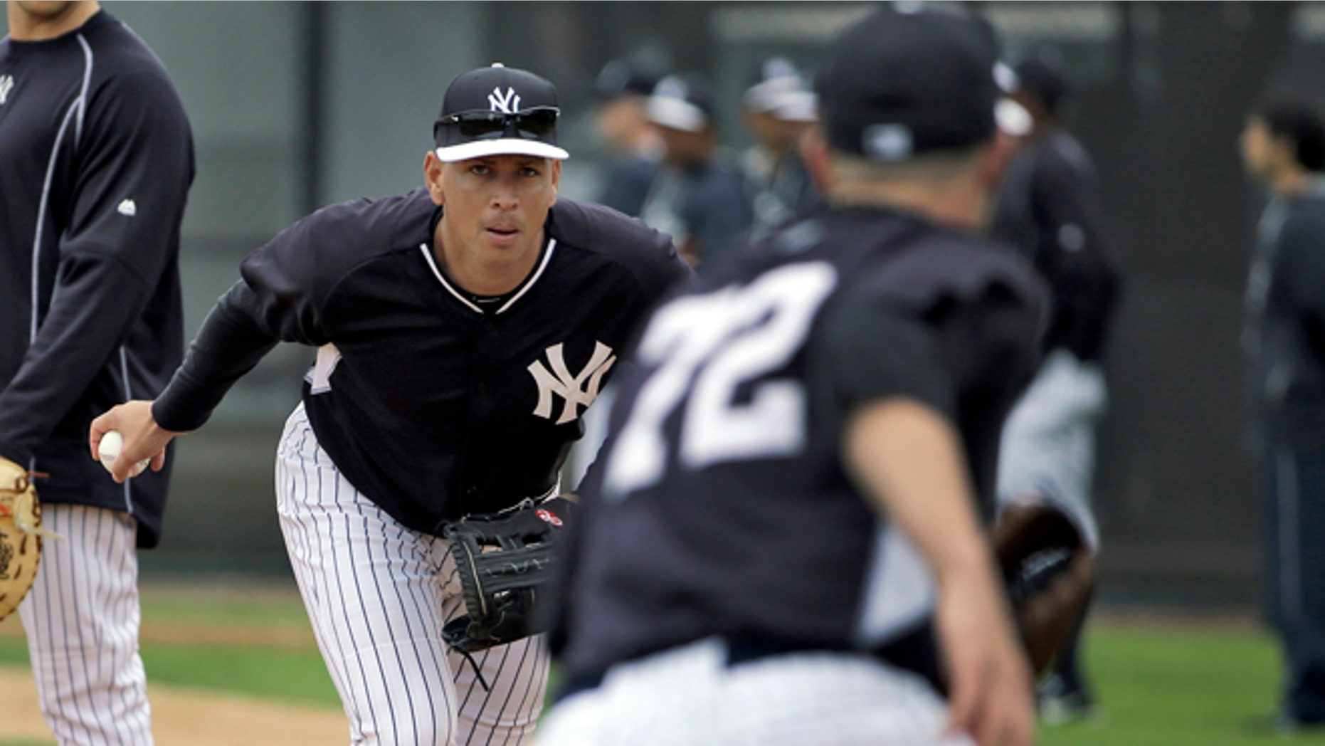 New York Yankees' Alex Rodriguez, center, flips the ball to pitcher Danny Burawa, right, as Mark Teixeira, left, looks on during workouts Friday, Feb. 27, 2015, in Tampa, Fla. Rodriguez was practicing at first base for the first time. (AP Photo/Chris O'Meara)