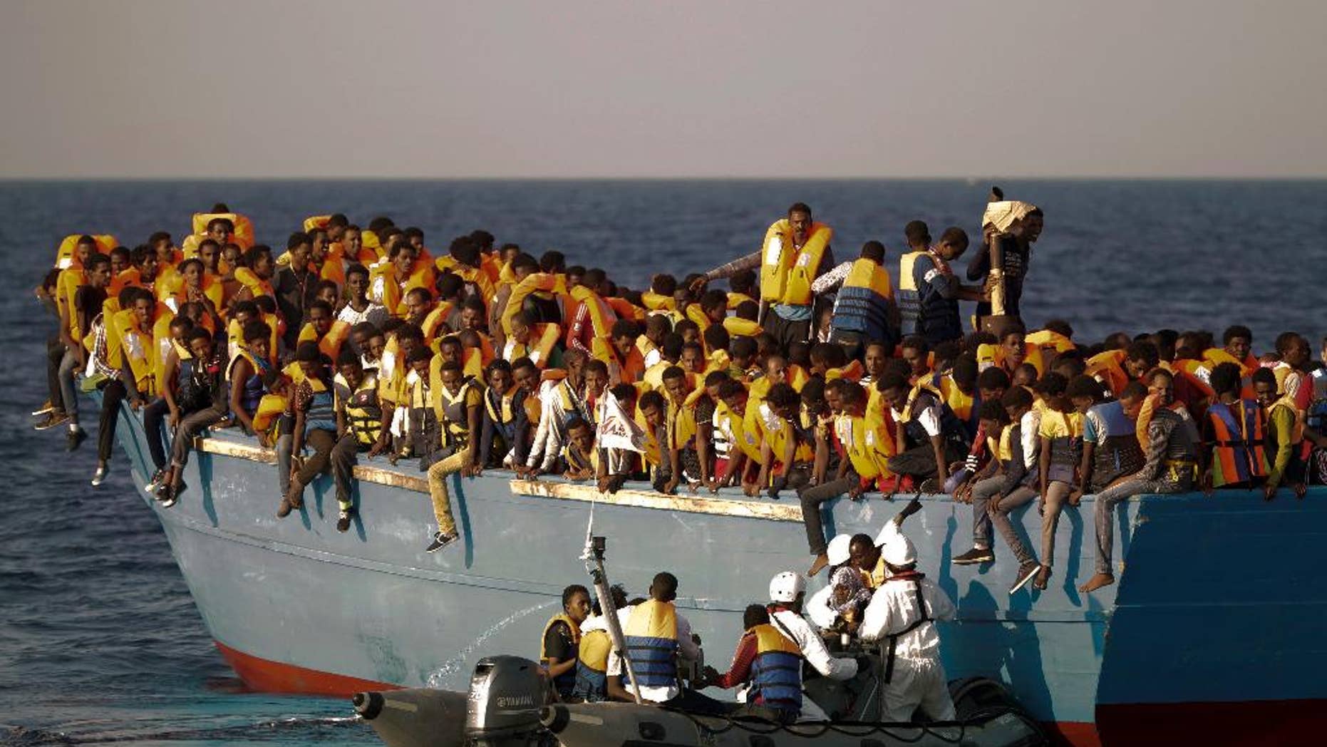 FILE - In this Monday, Aug. 29, 2016 file photo, migrants crowd onto a wooden boat as they wait to be rescued by members of an ONG at the Mediterranean sea, about 13 miles north of Sabratha, Libya. When the camera’s viewfinder is in “night vision” mode, a hidden world appears that is invisible to the naked eye in the darkness of night. Bathed in green, the view is even more dreamlike _ or nightmarish. (AP Photo/Emilio Morenatti, File)