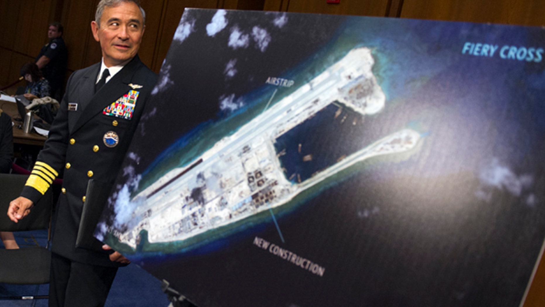 FILE - In this Sept. 17, 2015, file photo, Adm. Harry B. Harris, Jr., commander of U.S. Pacific Command, walks past a photograph showing an island that China is building on the Fiery Cross Reef in the South China Sea, as he prepares to testify on Capitol Hill in Washington before the Senate Armed Services Committee hearing on maritime security strategy in the Asia-Pacific region.