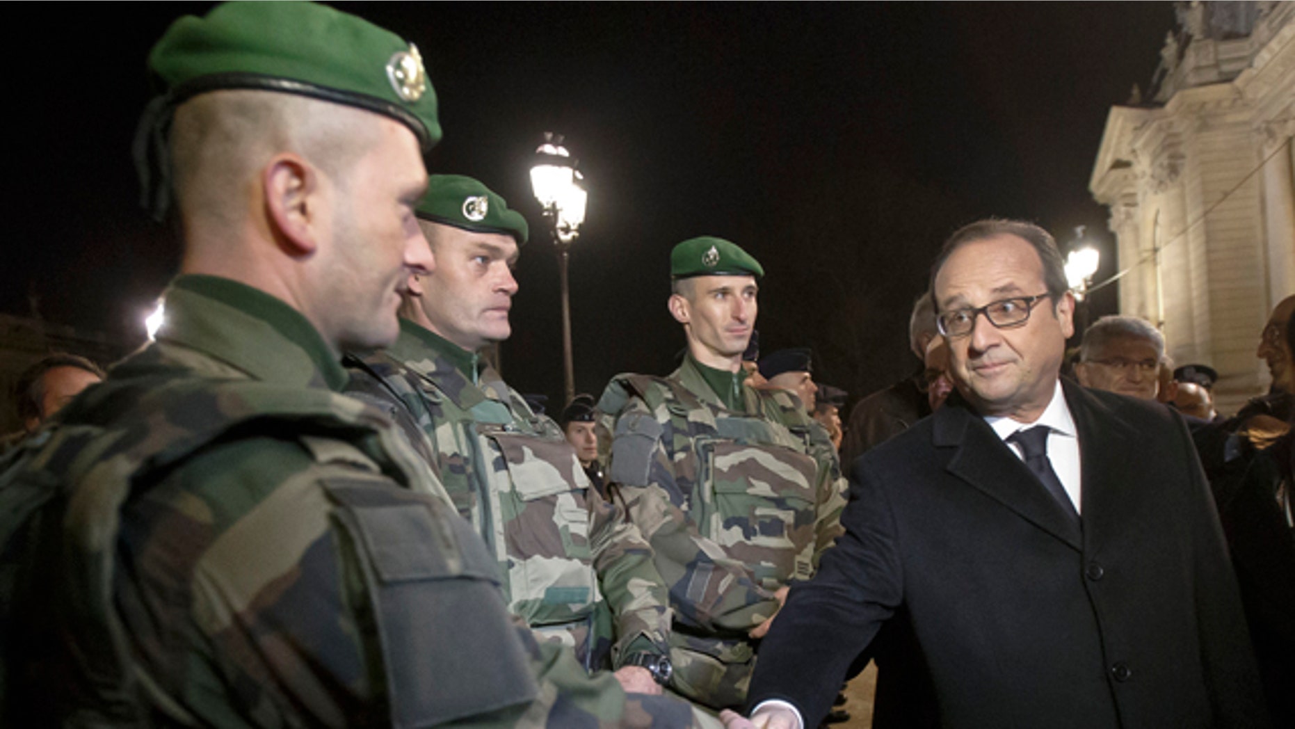 Dec. 31, 2015: France's President Francois Hollande, right, shakes hands with a foreign legionnaire as he visits the security measures at the Champs Elysees in Paris.