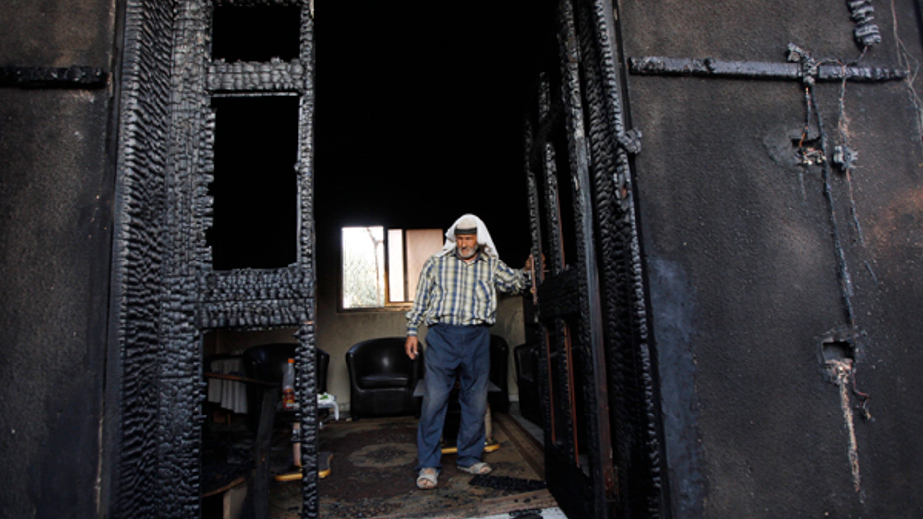 FILE - In this July 31, 2015 file photo, a Palestinian inspects a house after it was torched in a suspected attack by Jewish settlers, killing an 18-month-old Palestinian child and his parents, at Duma village near the West Bank city of Nablus.