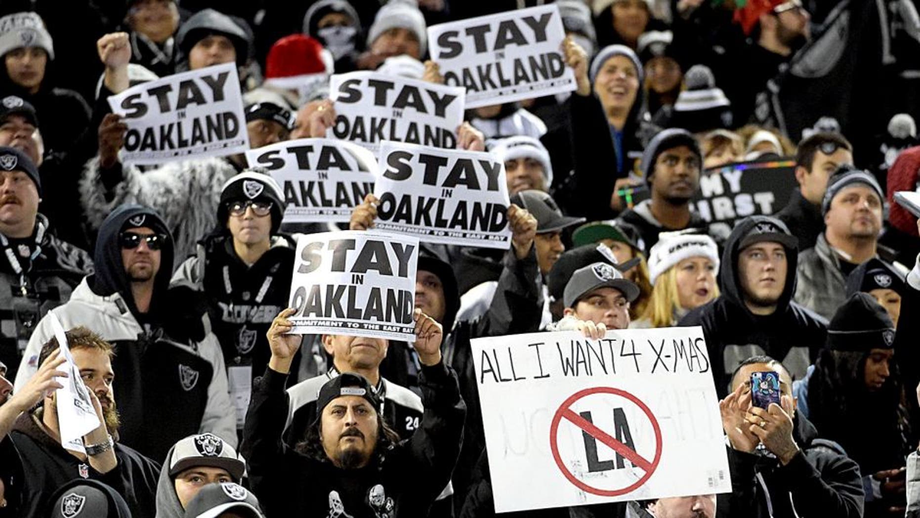 Dec 24, 2015; Oakland, CA, USA; Oakland Raiders fans hold signs that read "Stay in Oakland" in opposition of the Raiders potential move to Los Angeles during an NFL football game against the San Diego Chargers at O.co Coliseum. Mandatory Credit: Kirby Lee-USA TODAY Sports