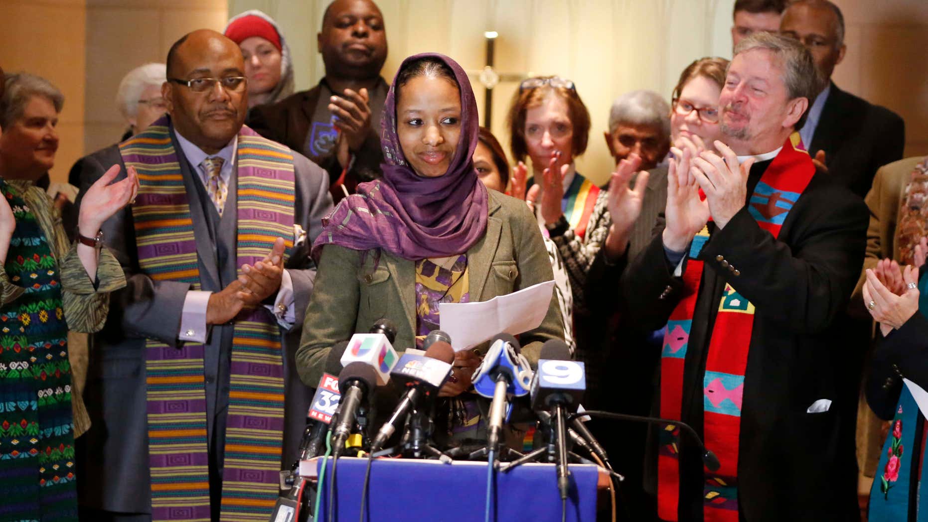 Dec. 16, 2015: Wheaton College associate professor Larycia Hawkins, center, is greeted with applause from supporters as she begins her remarks during a news conference in Chicago