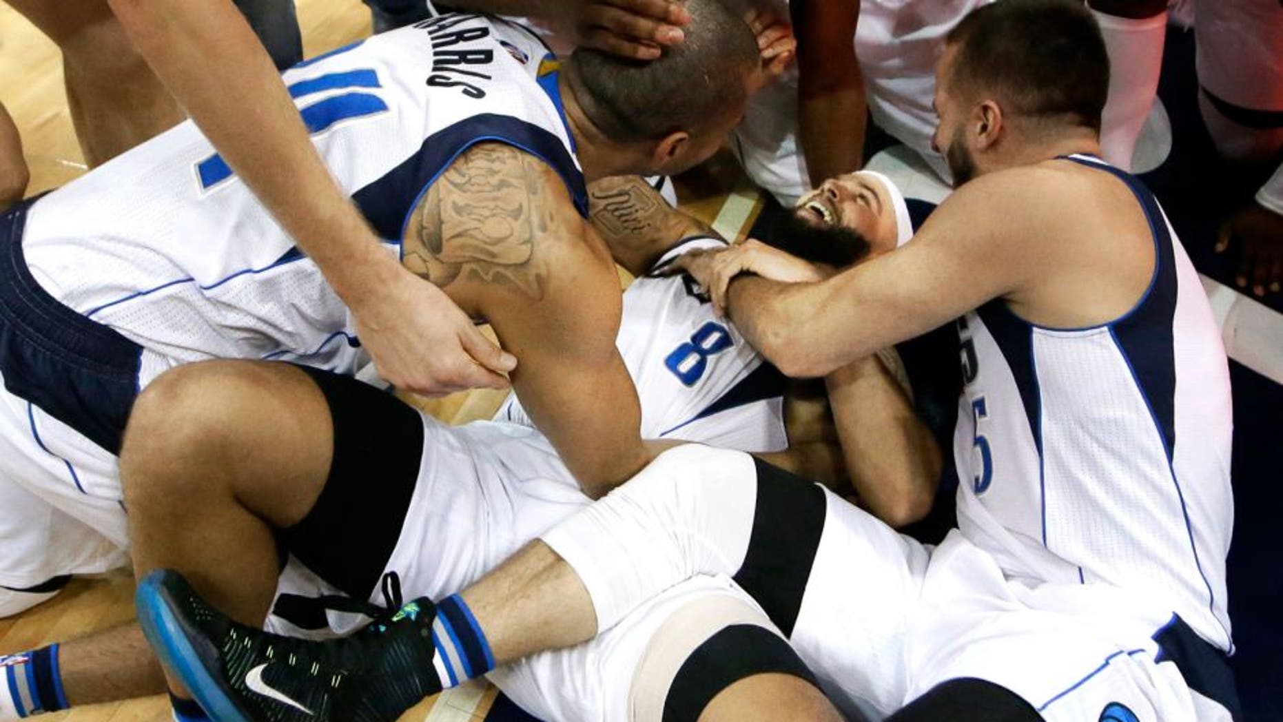 Dallas Mavericks guard Deron Williams (8) is mobbed by his teammates after scoring a 3-pointer in the final second of the second overtime in an NBA basketball game against the Sacramento Kings on Tuesday, Jan. 5, 2016, in Dallas. The Mavericks won 117-116. (AP Photo/LM Otero)