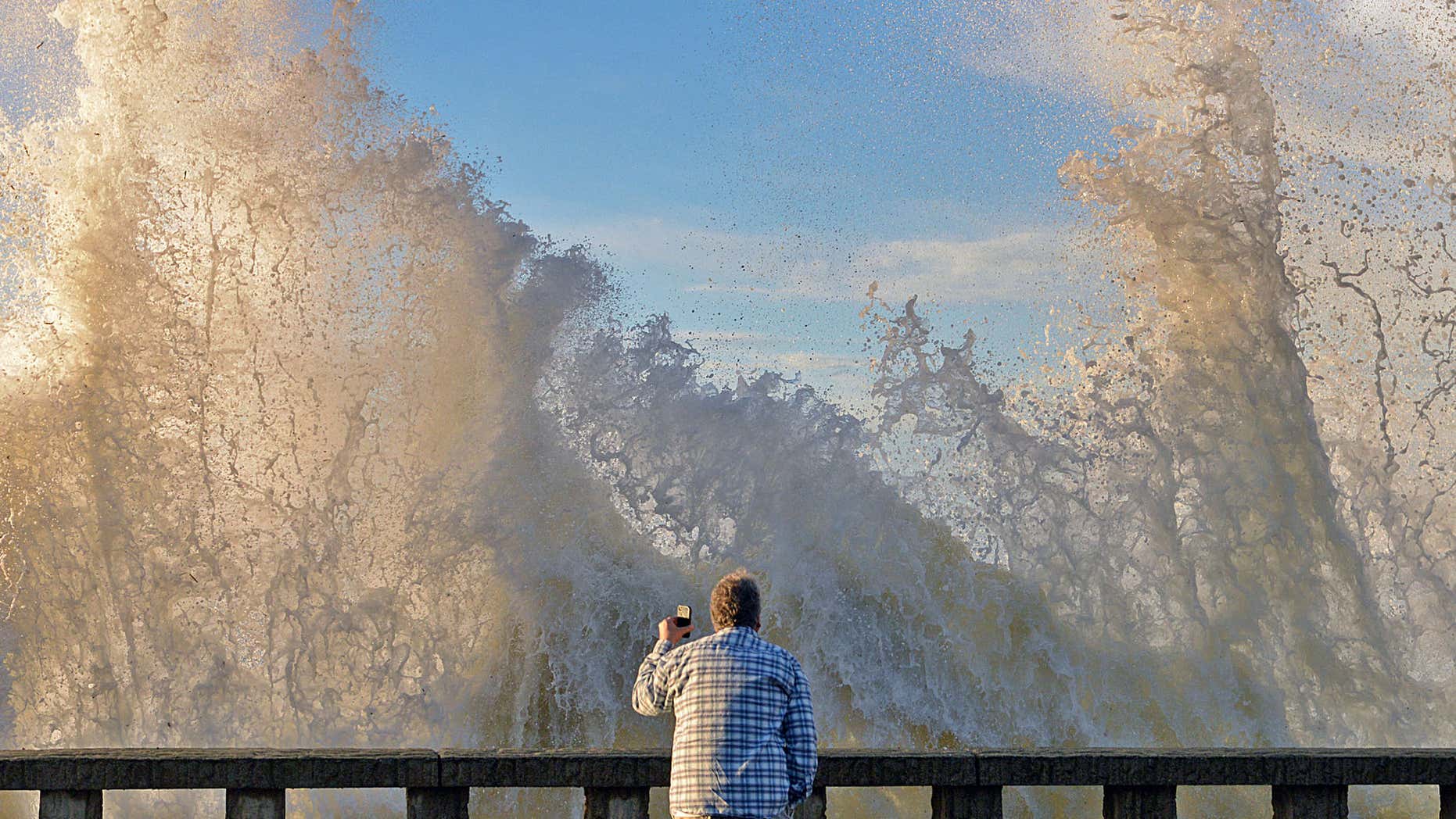 Jan. 7, 2016: In a photo provided by Mike Eliason, Bo Sailor of Goleta, Caif. watches as high surf crashes into the wall and spills onto Channel Drive in Montecito, Calif.