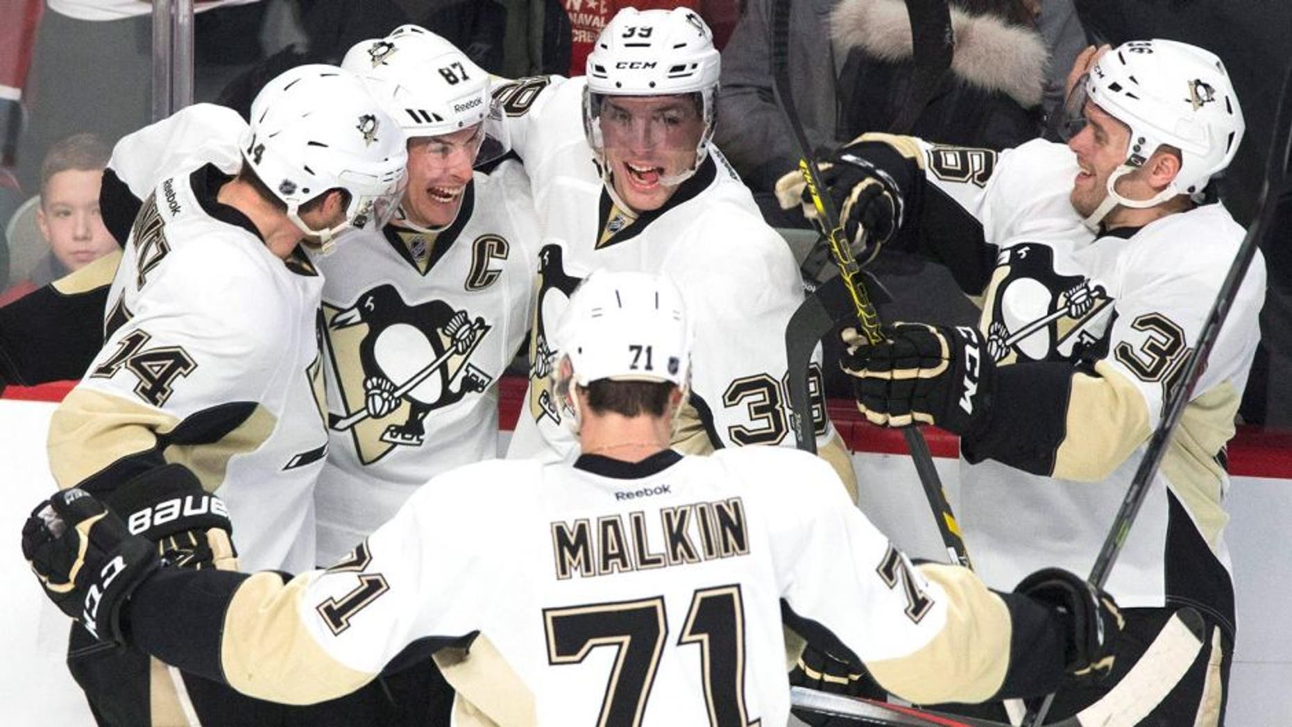 Pittsburgh Penguins' Sidney Crosby (87) celebrates with teammates David Perron (39), Chris Kunitz (14), Bryan Rust (36) and Evgeni Malkin after scoring against the Montreal Canadiens in overtime of an NHL hockey game Saturday, Jan. 10, 2015, in Montreal. (AP Photo/The Canadian Press, Graham Hughes)