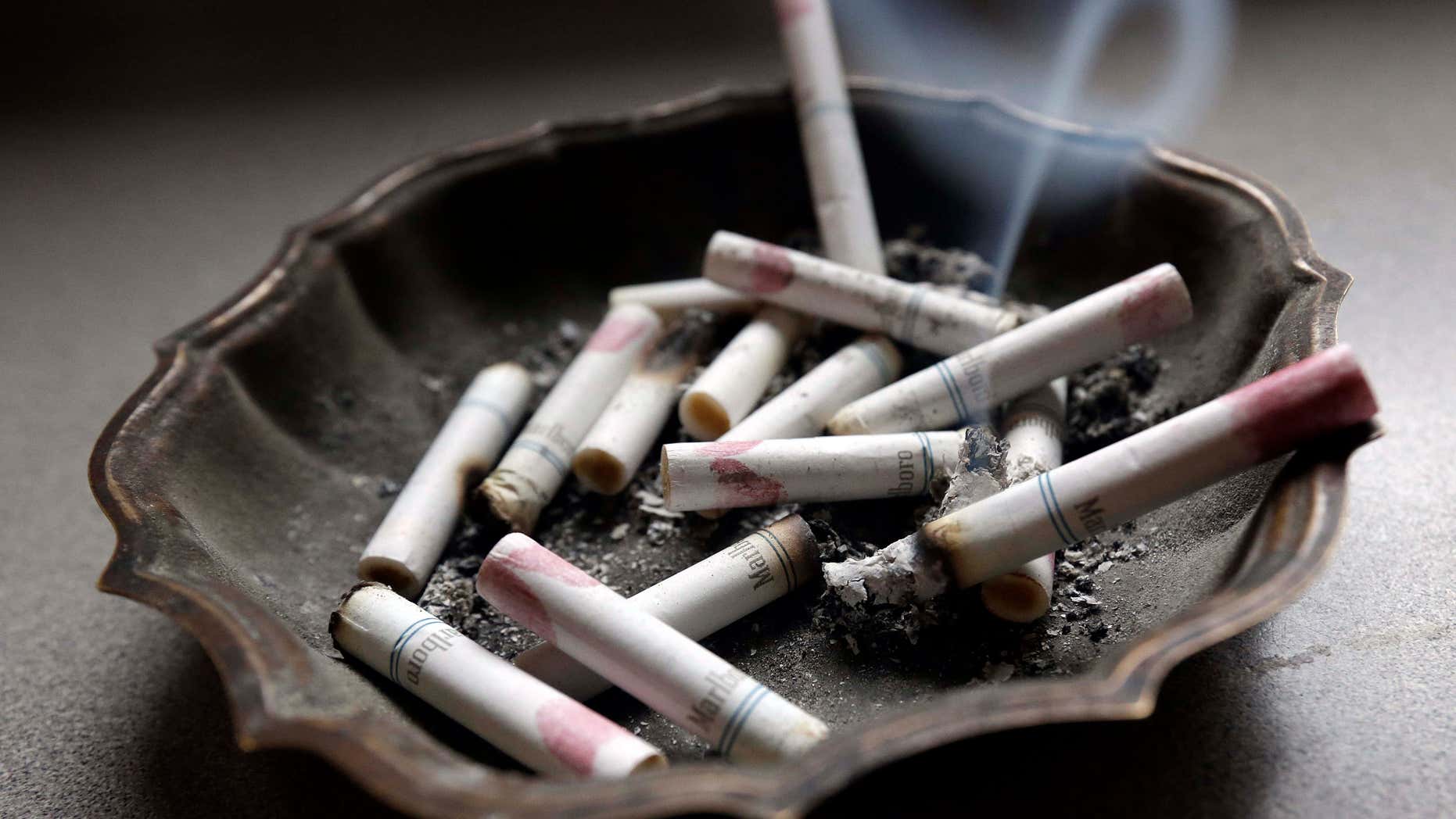 FILE - In this Saturday, March 2, 2013, photo, a cigarette burns in an ashtray at a home in Hayneville, Ala.