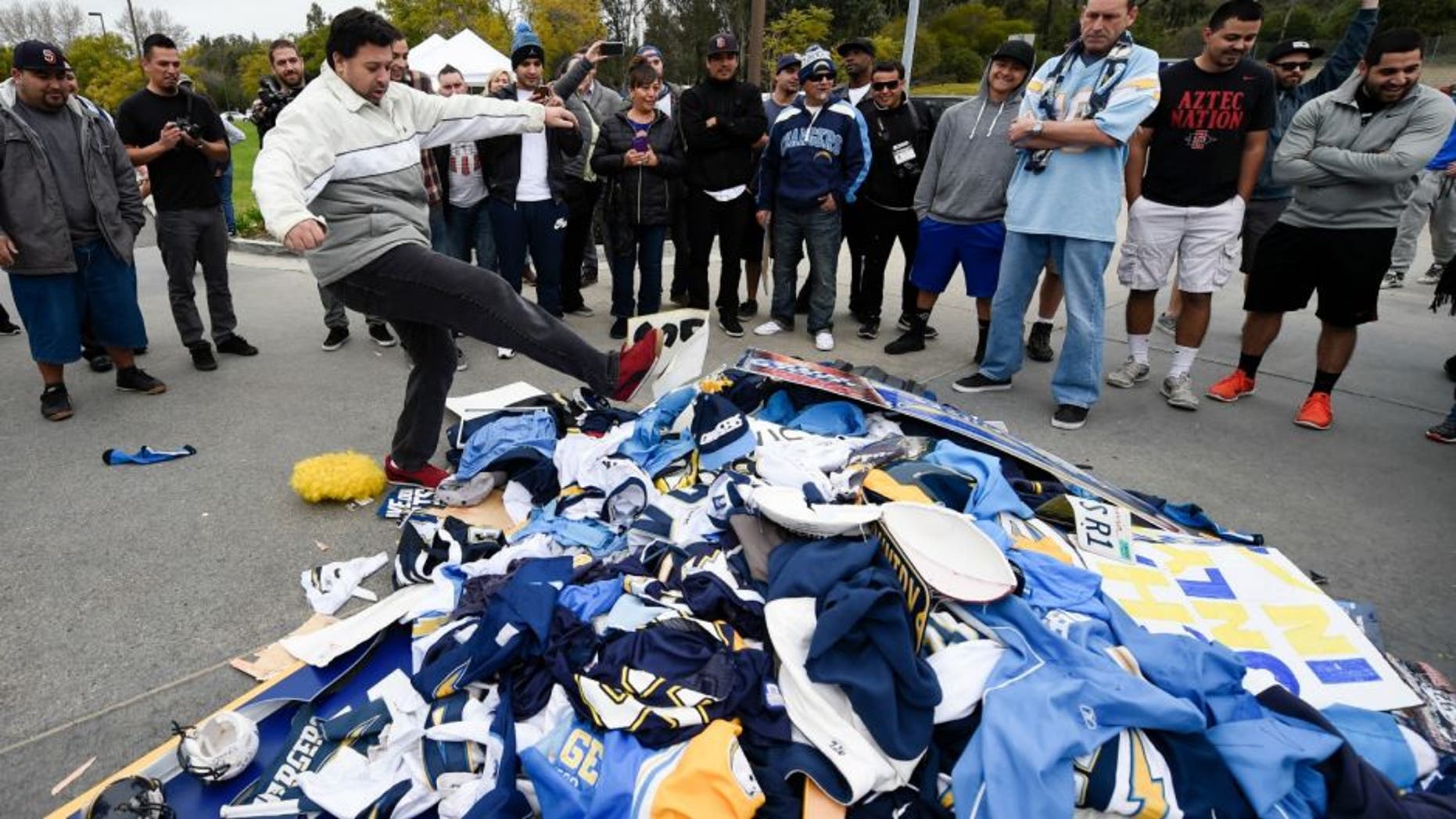Chris Githens, left, kicks a pile of Chargers memorabilia in front of San Diego Chargers headquarters after the team announced that it will move to Los Angeles Thursday Jan. 12, 2017, in San Diego. (AP Photo/Denis Poroy)