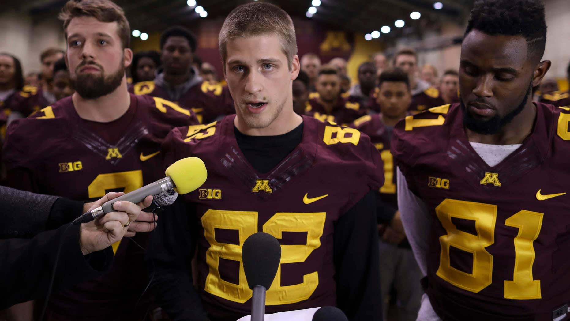 FILE - In this Dec. 15, 2016, file photo, University of Minnesota wide receiver Drew Wolitarsky, flanked by quarterback Mitch Leidner, left, and tight end Duke Anyanwu stands in front of other team members as he reads a statement on behalf of the players in the Nagurski Football Complex in Minneapolis, Minn.